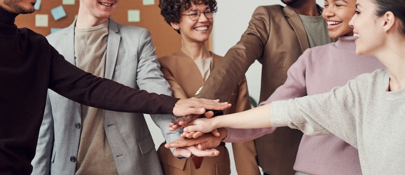 pexels photo 3184424 3184424 A group of happy, diverse colleagues celebrating teamwork and cooperation with a group high five indoors.