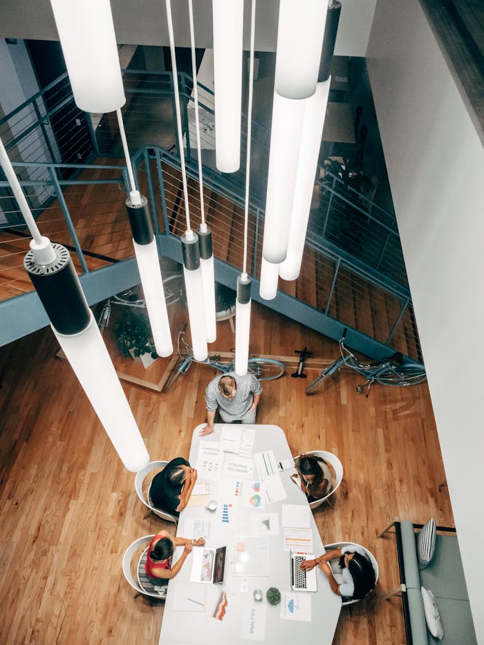 who-we-are High angle shot of team collaborating at a stylish desk with ceiling lights in a modern office.